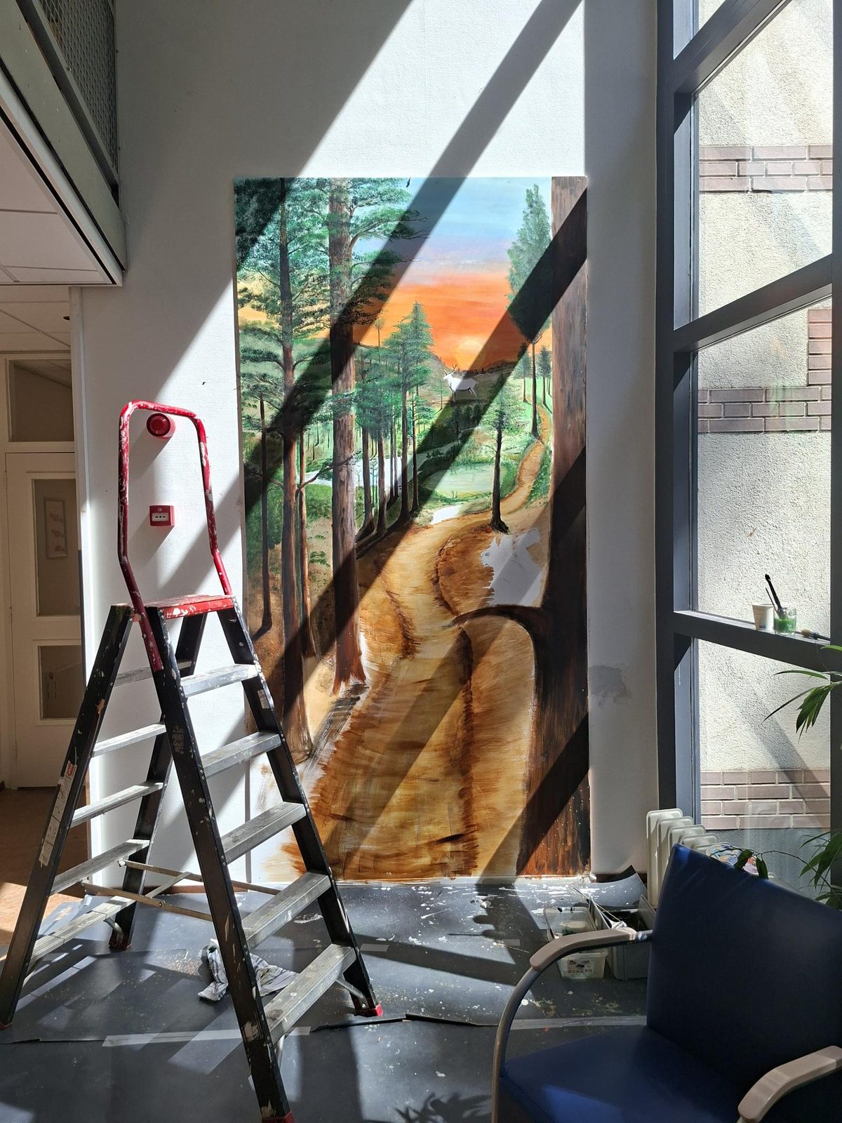 De muurschildering in de hal, met strijklicht door de hoge ramen